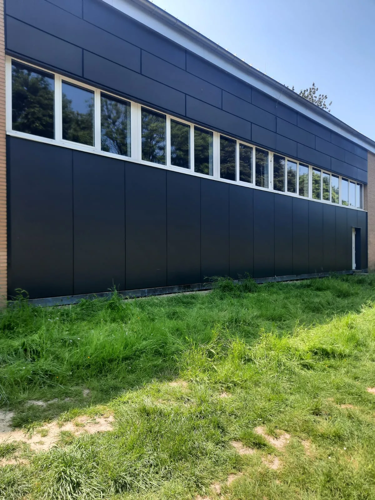 Neue vorgehängte Fassade aus dunklen HPL-Platten an einer Schule in Kamp-Lintfort