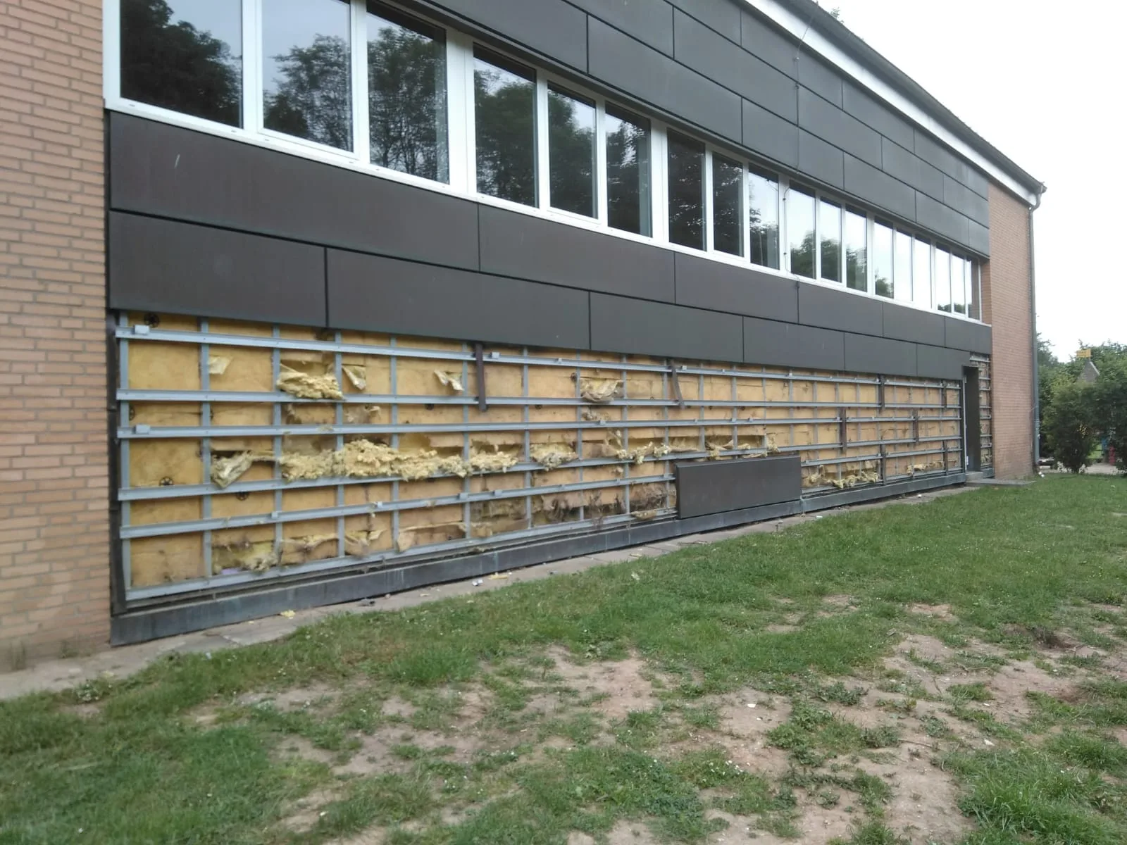 Beschädigte Fassade einer Schule in Kamp-Lintfort mit freiliegender Dämmung nach Vandalismus