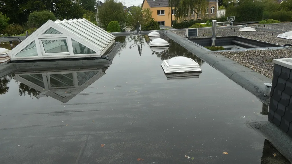 Flachdach in Köln vor der Sanierung mit großer stehender Wasserfläche um die Lichtkuppel – vorher