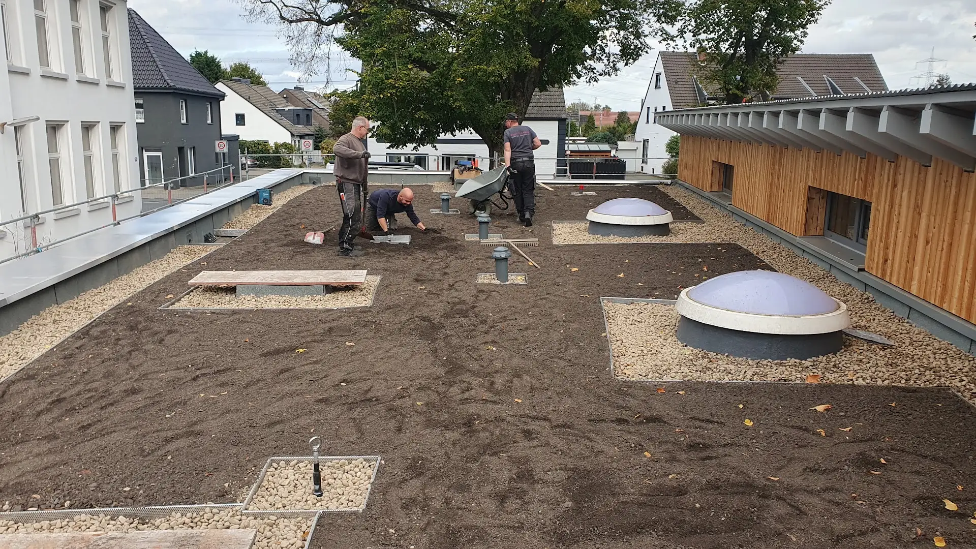 Dachdecker bringen Substrat für das Gründach auf dem Flachdach einer Kita in Moers ein