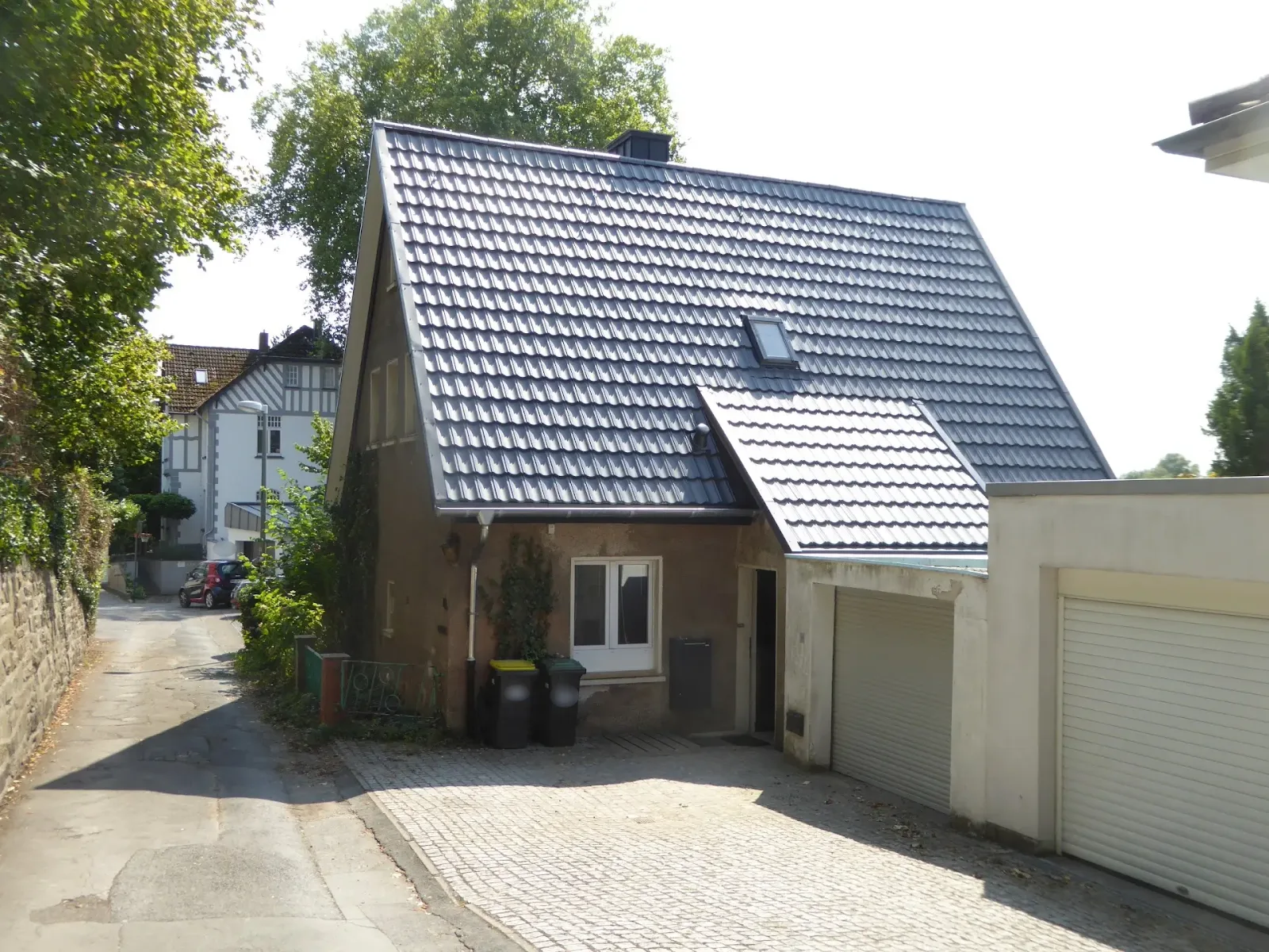 Wohnhaus in Mülheim an der Ruhr nach der Dachsanierung mit Metalldach in Ziegeloptik und neuem Dachfenster