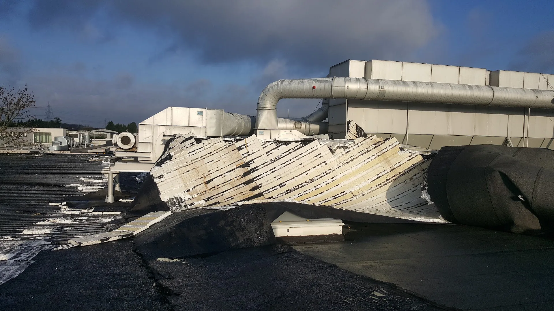 Vom Sturm abgerissene Dachbleche und Dämmung auf einem Industrie-Flachdach