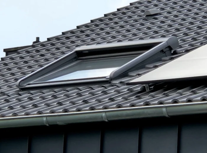 Geöffnetes Dachfenster in neu eingedecktem Steildach mit dunklen Dachsteinen in Goch