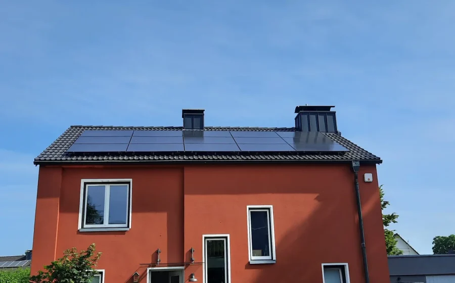 Wohnhaus mit roter Fassade, neu eingedecktem Steildach und Full-Black-PV-Anlage in Moers