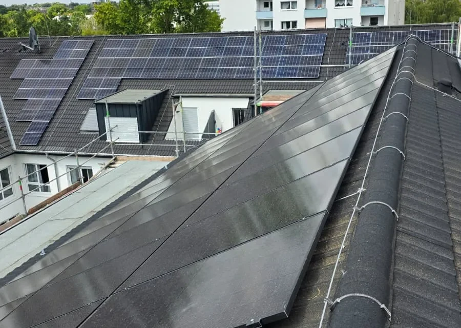 Schwarze PV-Module auf neu eingedecktem Steildach eines Wohnheims in Düsseldorf
